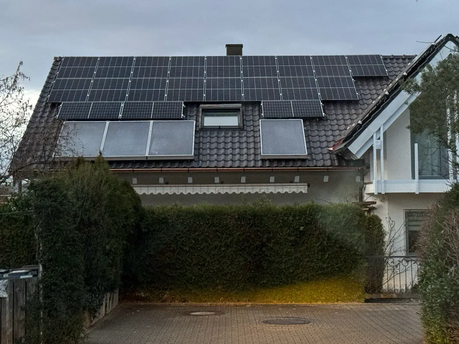 Ziegeldach eines Wohnhauses mit Photovoltaikmodulen, darunter Solarthermie-Kollektoren