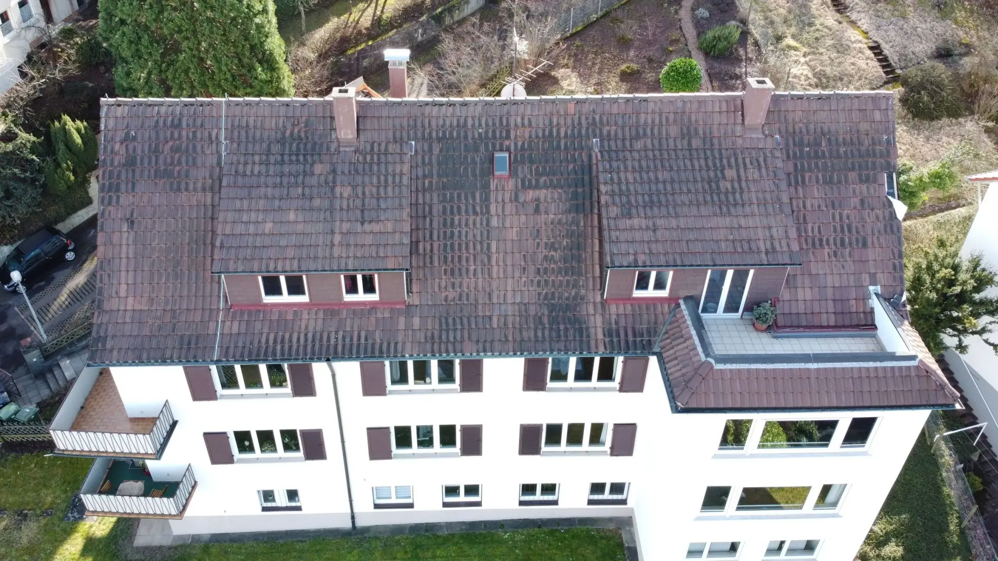Mehrfamilienhaus in Stuttgart vor der Sanierung: altes, bemoostes Ziegeldach mit zwei Gauben