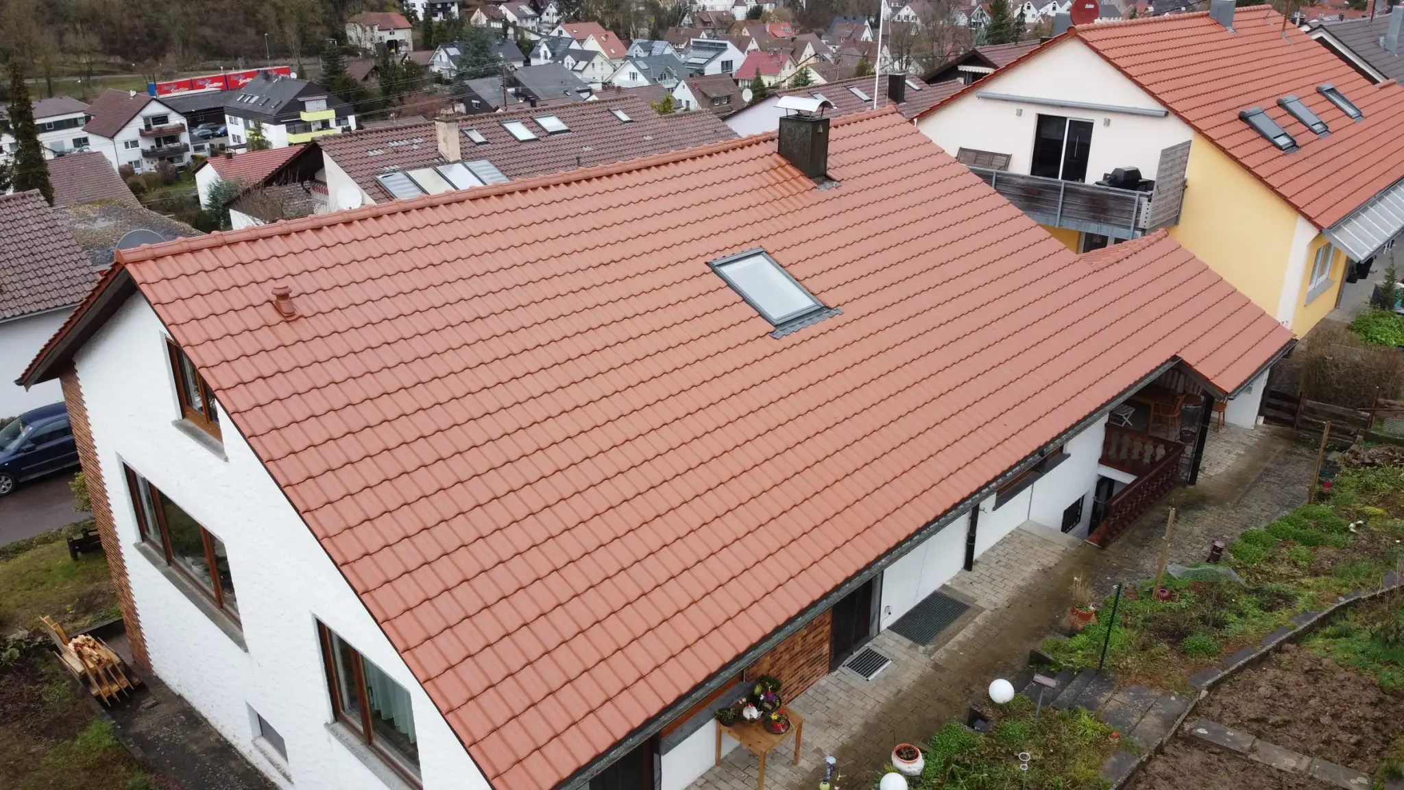 Fertig eingedecktes rotes Ziegeldach des Einfamilienhauses mit Dachfenster